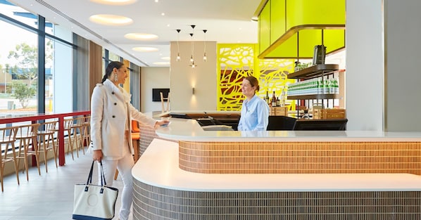 Un moderno vestíbulo de hotel con mostrador de recepción, zona de estar y vistas al exterior.