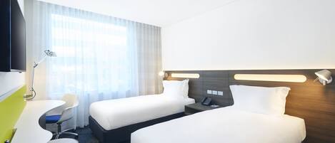 Una habitación de hotel con dos camas, un escritorio, una silla, un televisor y una lámpara.