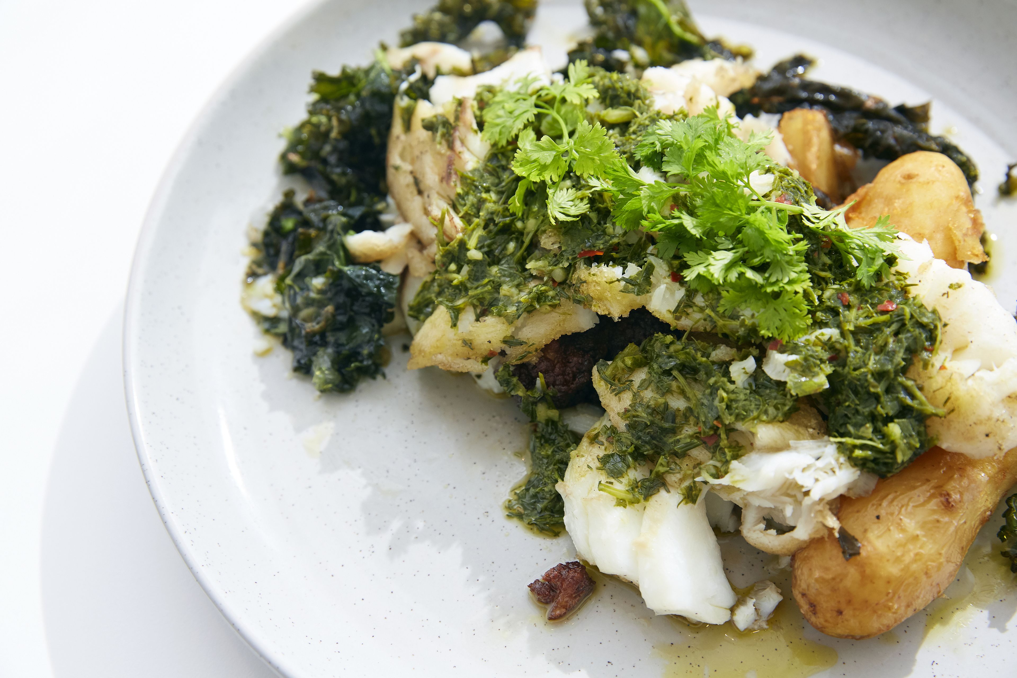 A plate of food with various ingredients including greens, herbs, and possibly some meat or seafood.