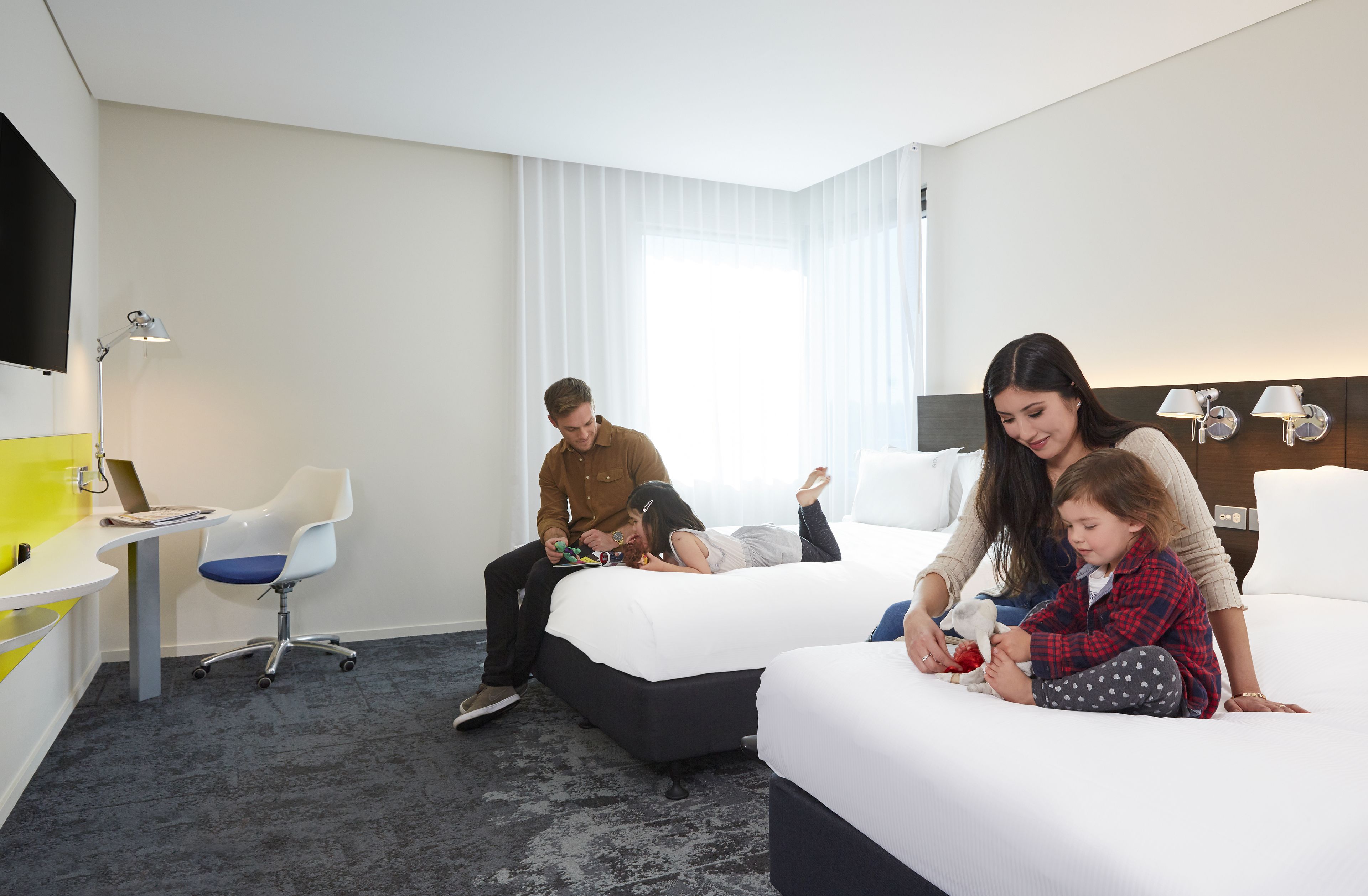 A hotel room with a bed, a desk, a chair, and a TV.