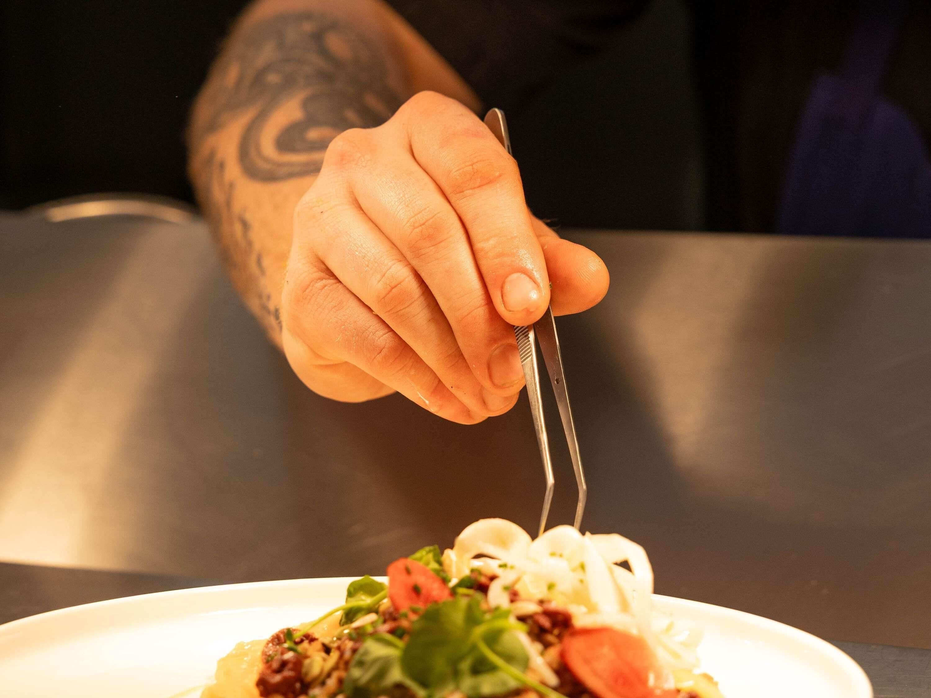 Una mano sosteniendo un tenedor sobre un plato de comida.