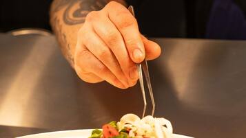 Una mano sosteniendo un tenedor sobre un plato de comida.