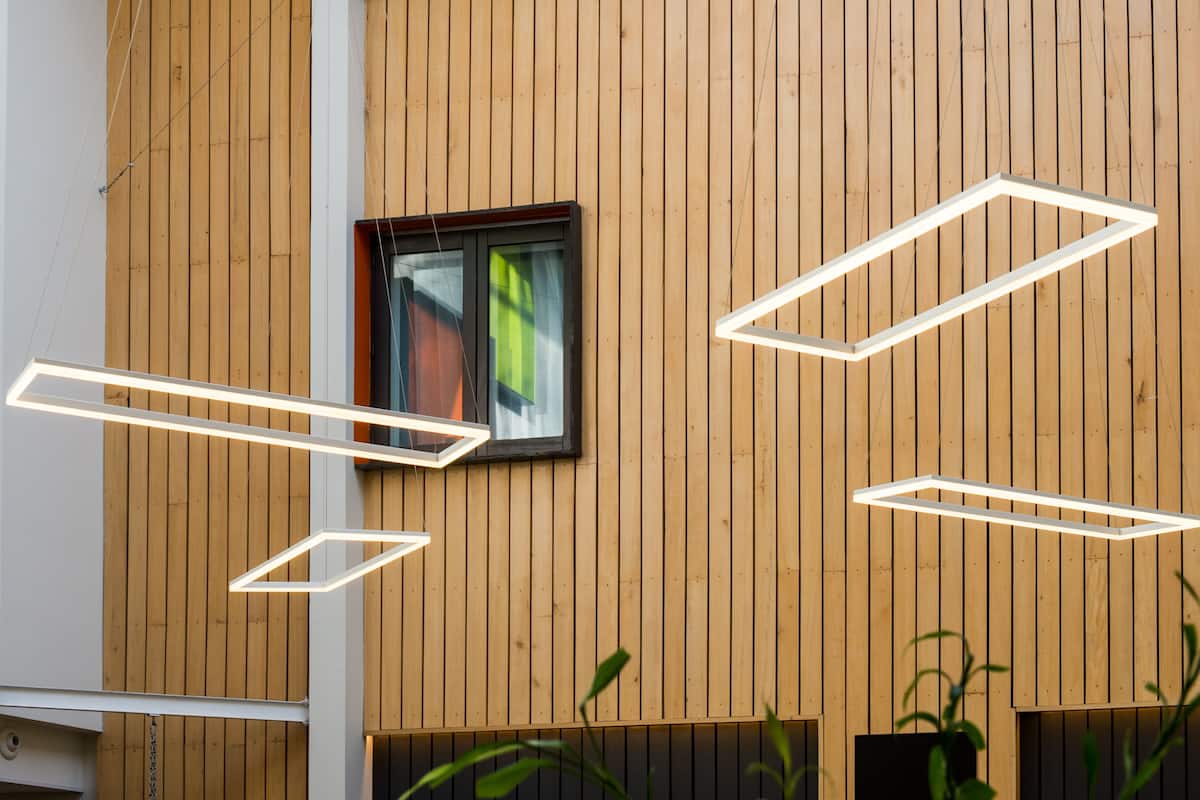 A modern building with wooden panel walls, a window with a view, and geometric light fixtures.
