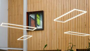 A modern building with wooden panel walls, a window with a view, and geometric light fixtures.