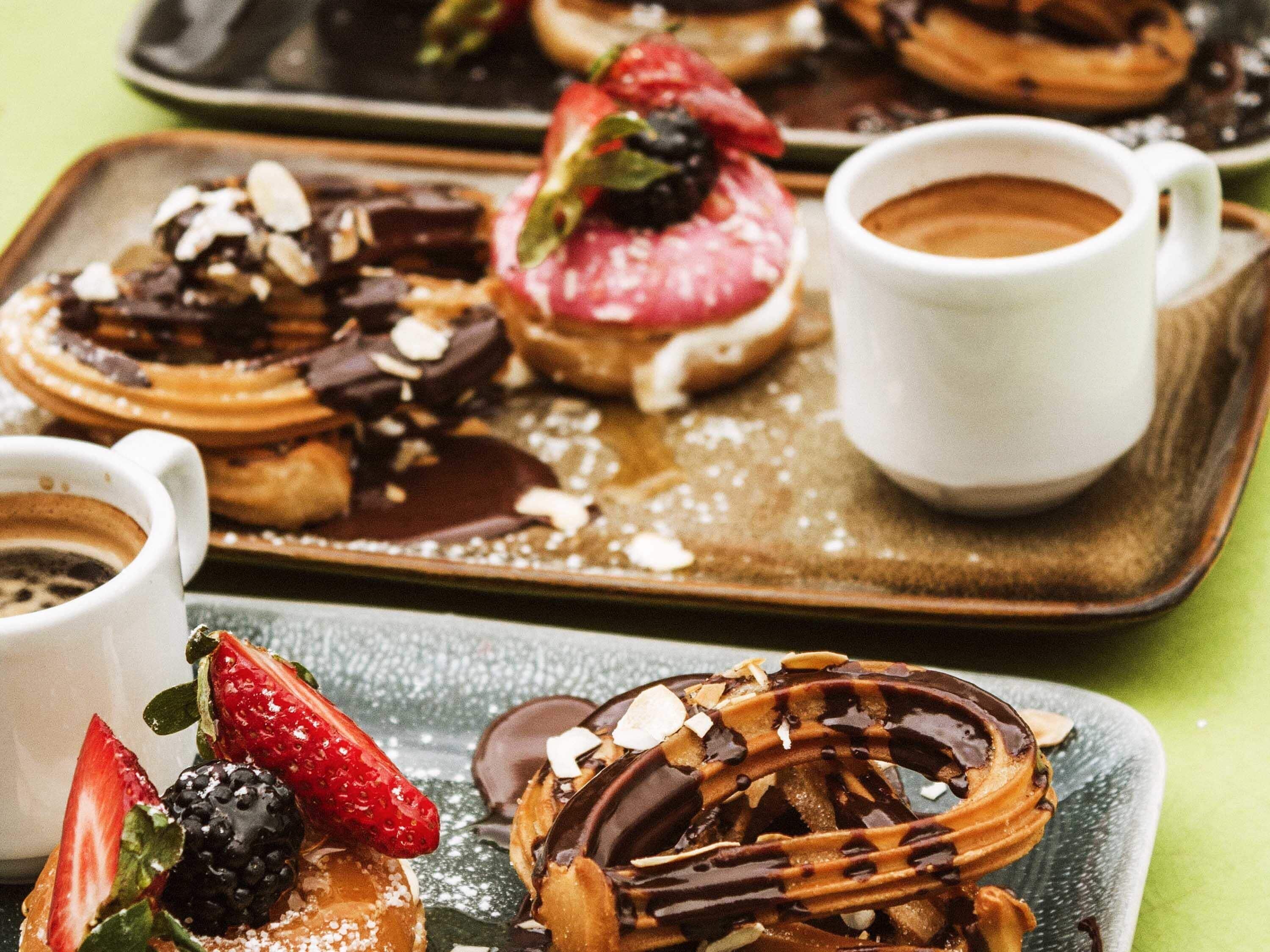 A tray of assorted pastries and a cup of coffee on a table.