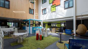 A modern indoor space with a bar area, seating arrangements, and a staircase leading to upper levels.