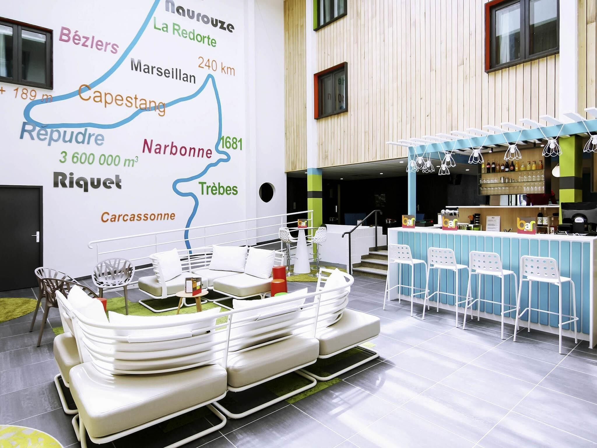 A modern bar area with white bar stools and a map on the wall.