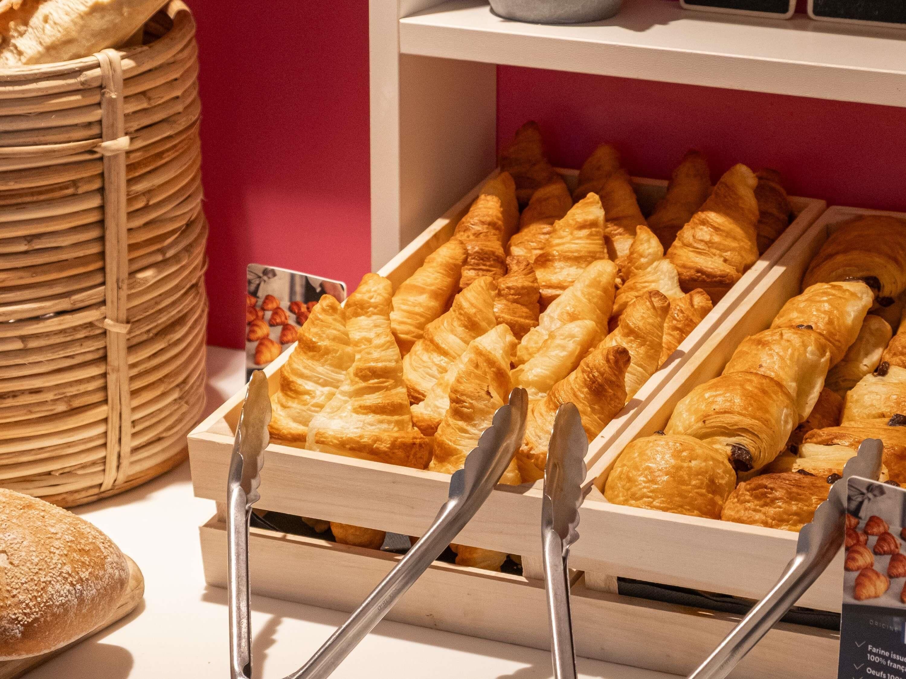 Une vitrine de boulangerie présentant diverses pâtisseries et pains, notamment des croissants et des baguettes.