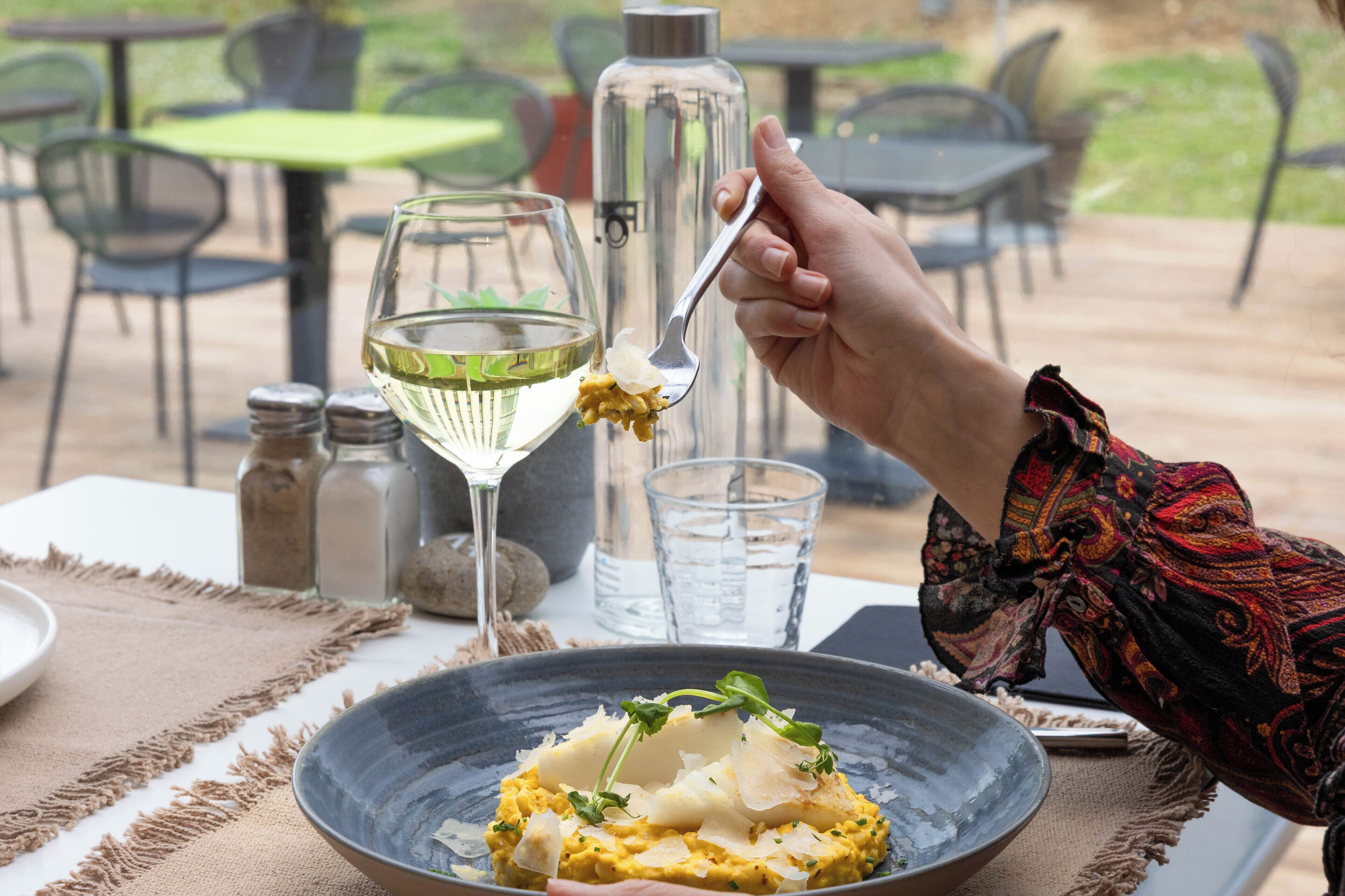 A dining table with a plate of food, a glass of white wine, and a water glass.