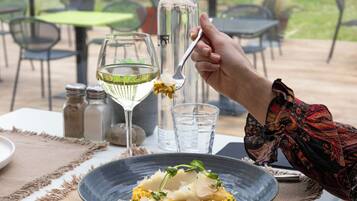 A dining table with a plate of food, a glass of white wine, and a water glass.