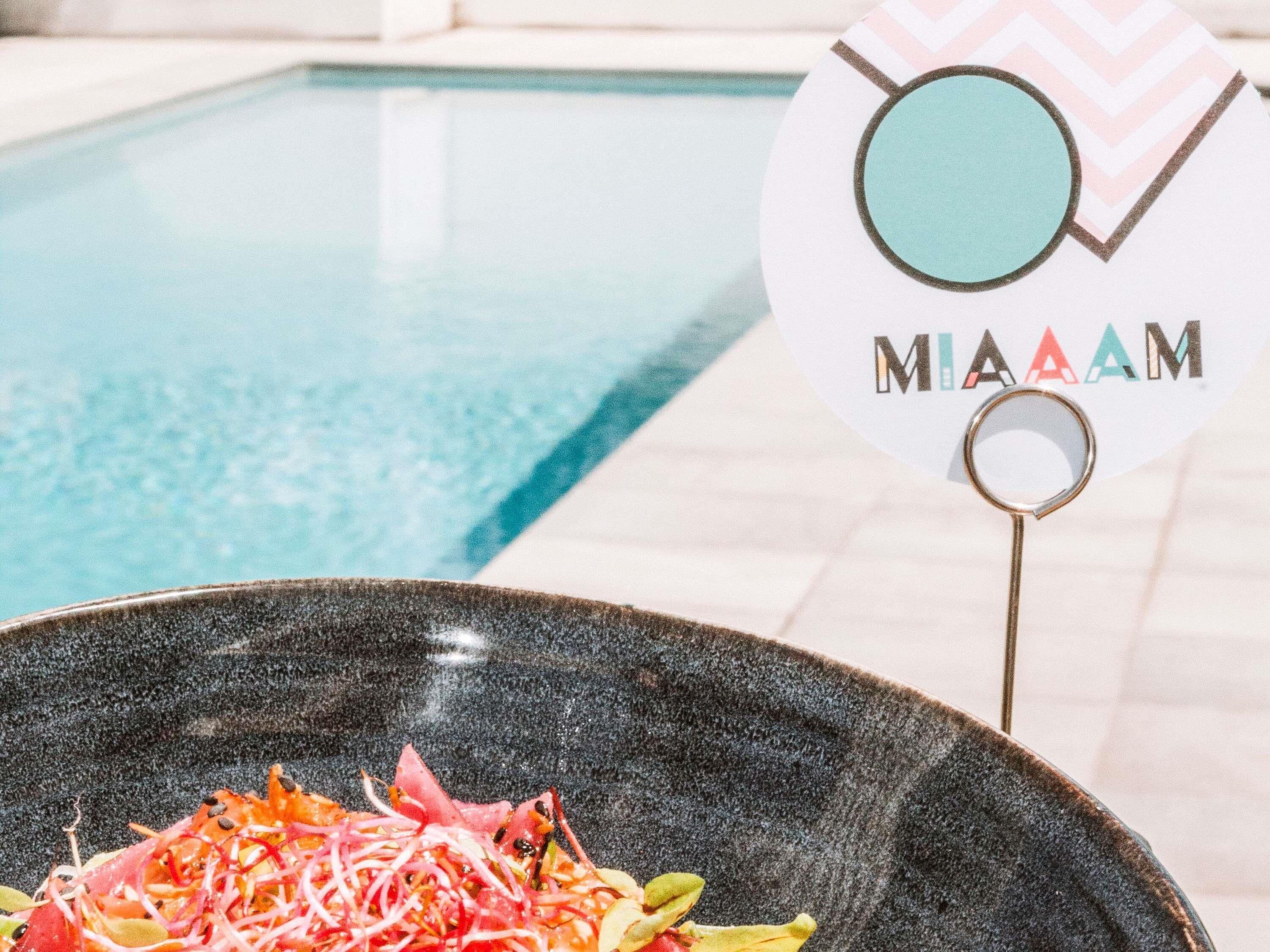 Une vue sur la piscine avec un panneau indiquant « MADAME » et un saladier rempli de salade.