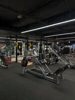 Un gimnasio con diverso equipo de levantamiento de pesas, bancos y discos.