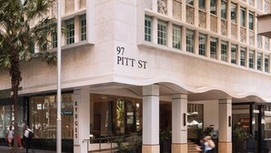 Edifici modern amb l'adreça 97 Pitt St. Té grans finestres, una entrada destacada i una palmera propera.