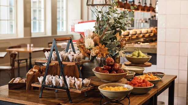 Un aparador de bufet amb diverses fruites, pastissos i un centre de taula floral.