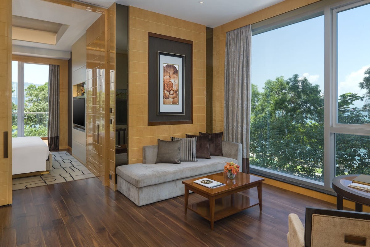 Een moderne hotelkamer met een groot raam, een bank, een salontafel en een televisie.