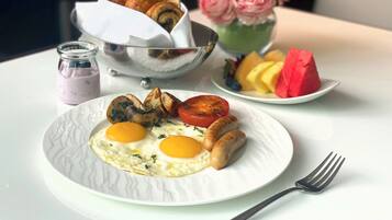 Un plato de desayuno con huevos, salchichas, champiñones y tomates.