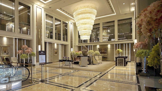 A spacious lobby with a large chandelier, seating areas, and decorative plants. - The Olympian Hong Kong (Kowloon)