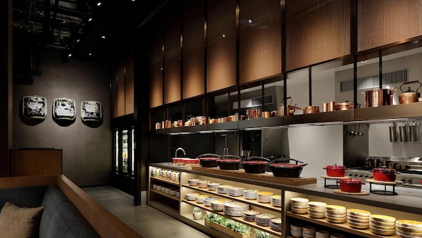 A modern kitchen with stainless steel appliances, wooden shelves with dishes, and a seating area with a sofa and cushions. - Aloft by Marriott Osaka Umeda (Osaka)