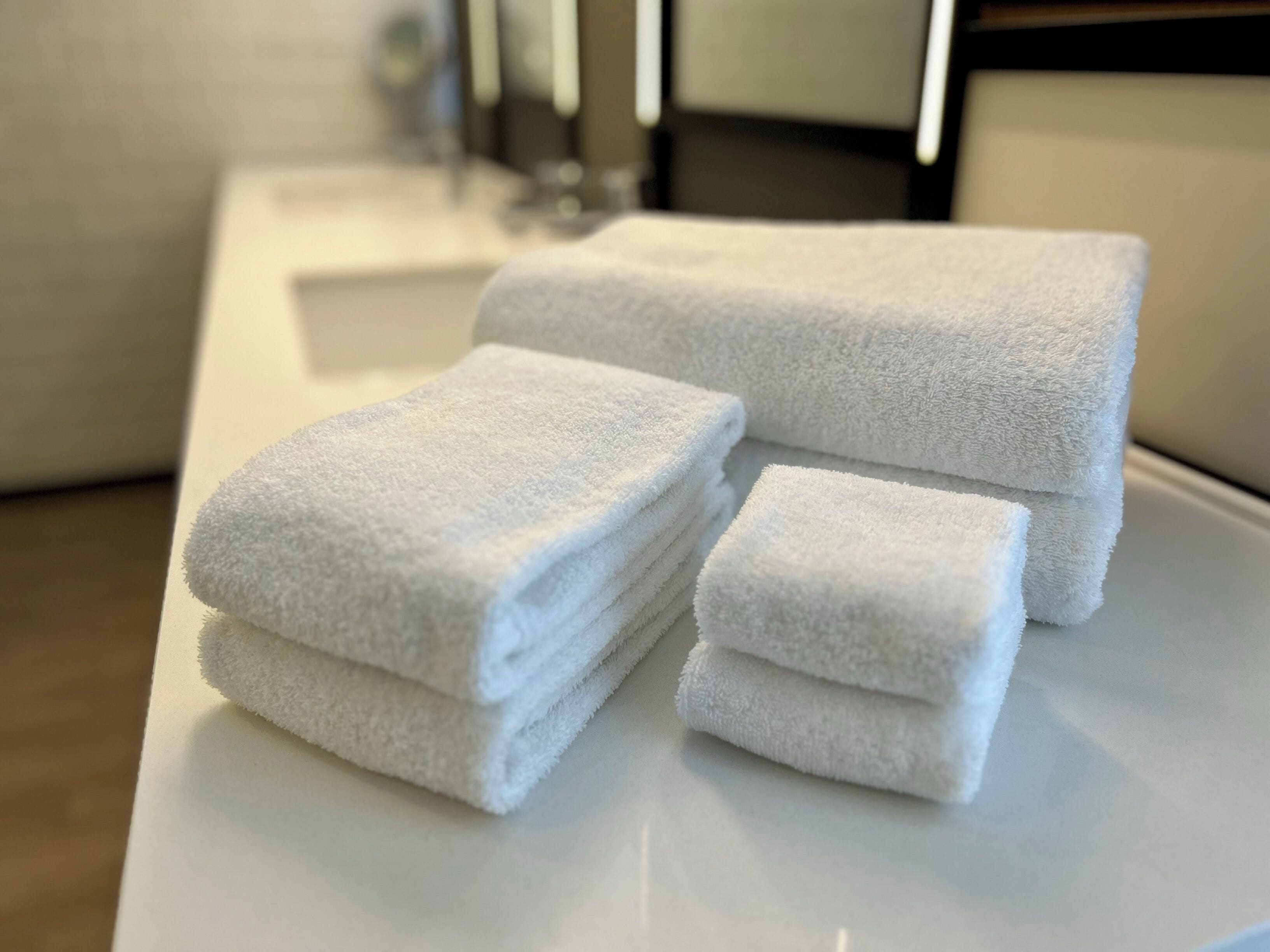A stack of white towels on a white surface in a bathroom.