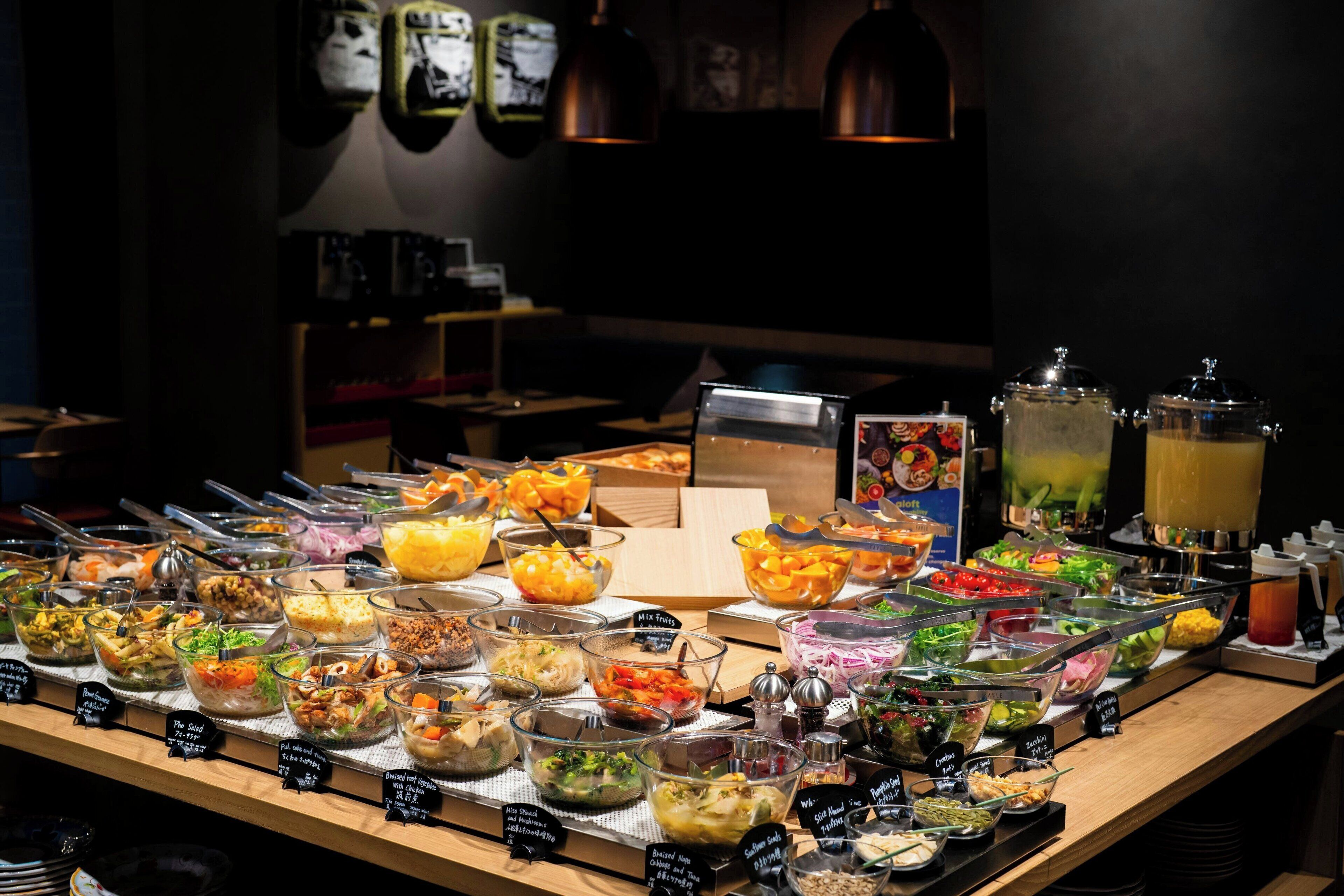 En buffet med et udvalg af mad, herunder salater, frugt og drikkevarer.
