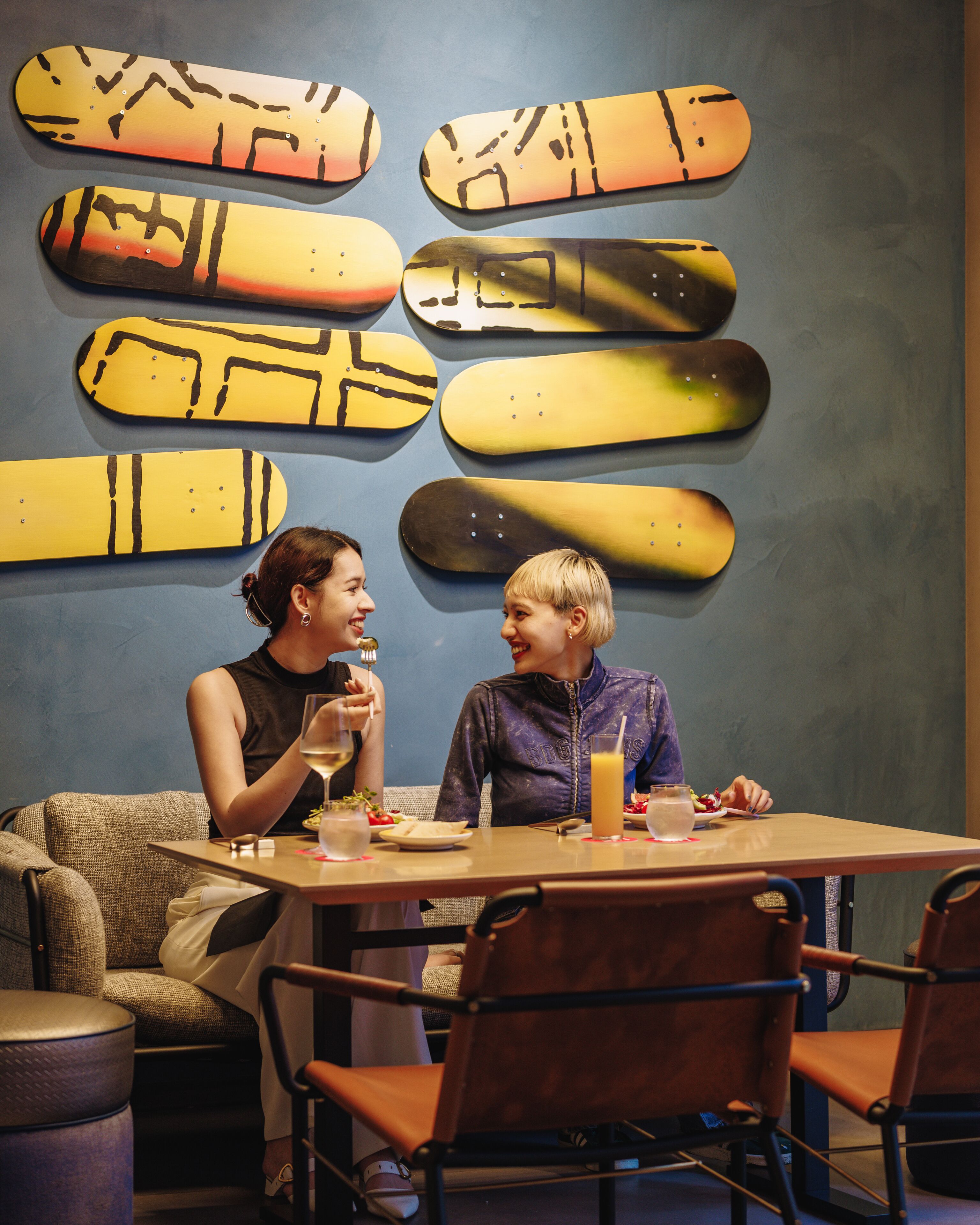 Un coin repas comprenant une table, des chaises et un mur décoré de planches de snowboard.