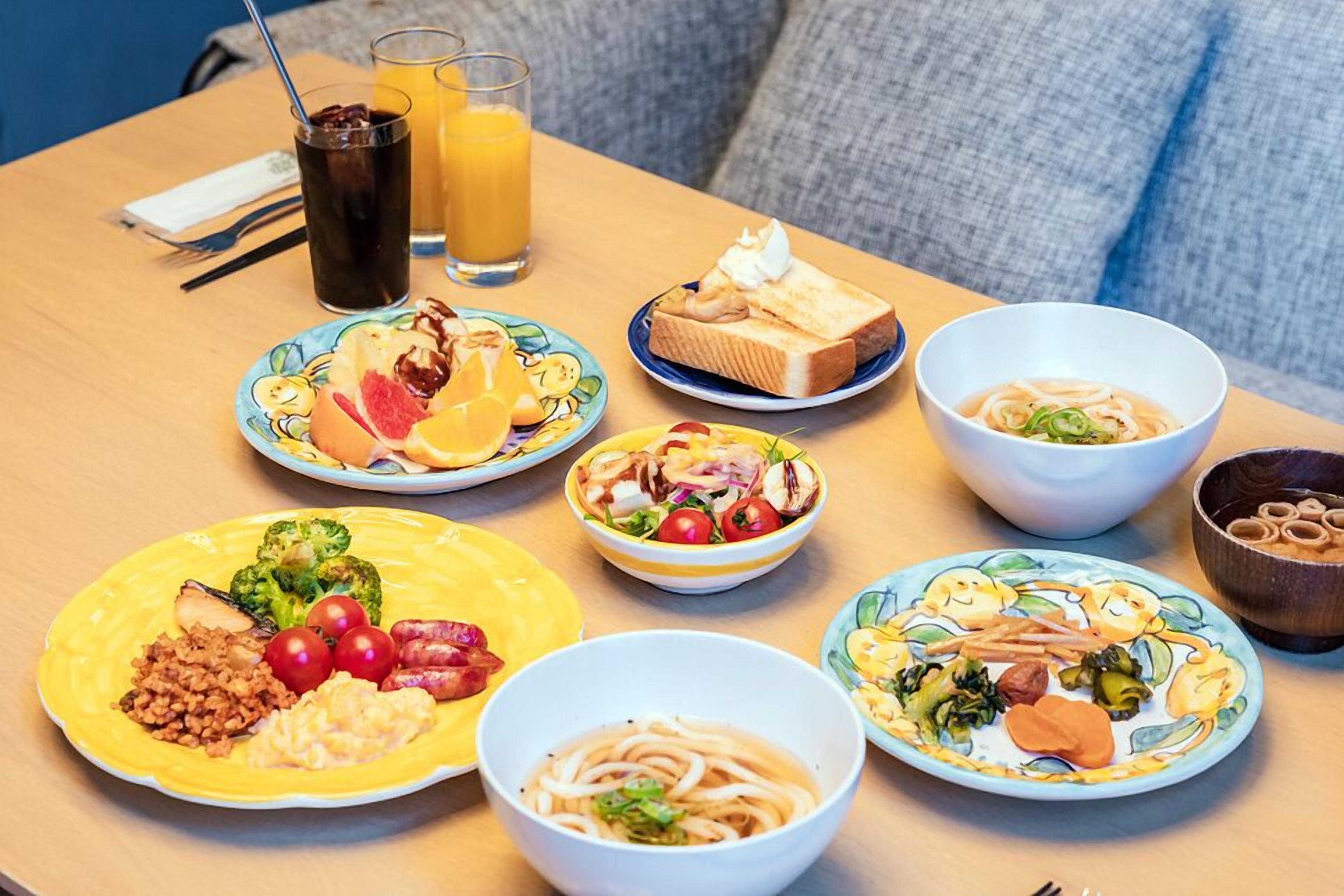 Una mesa con varios platos, incluyendo un pastel, un tazón de sopa y una porción de verduras y carne.