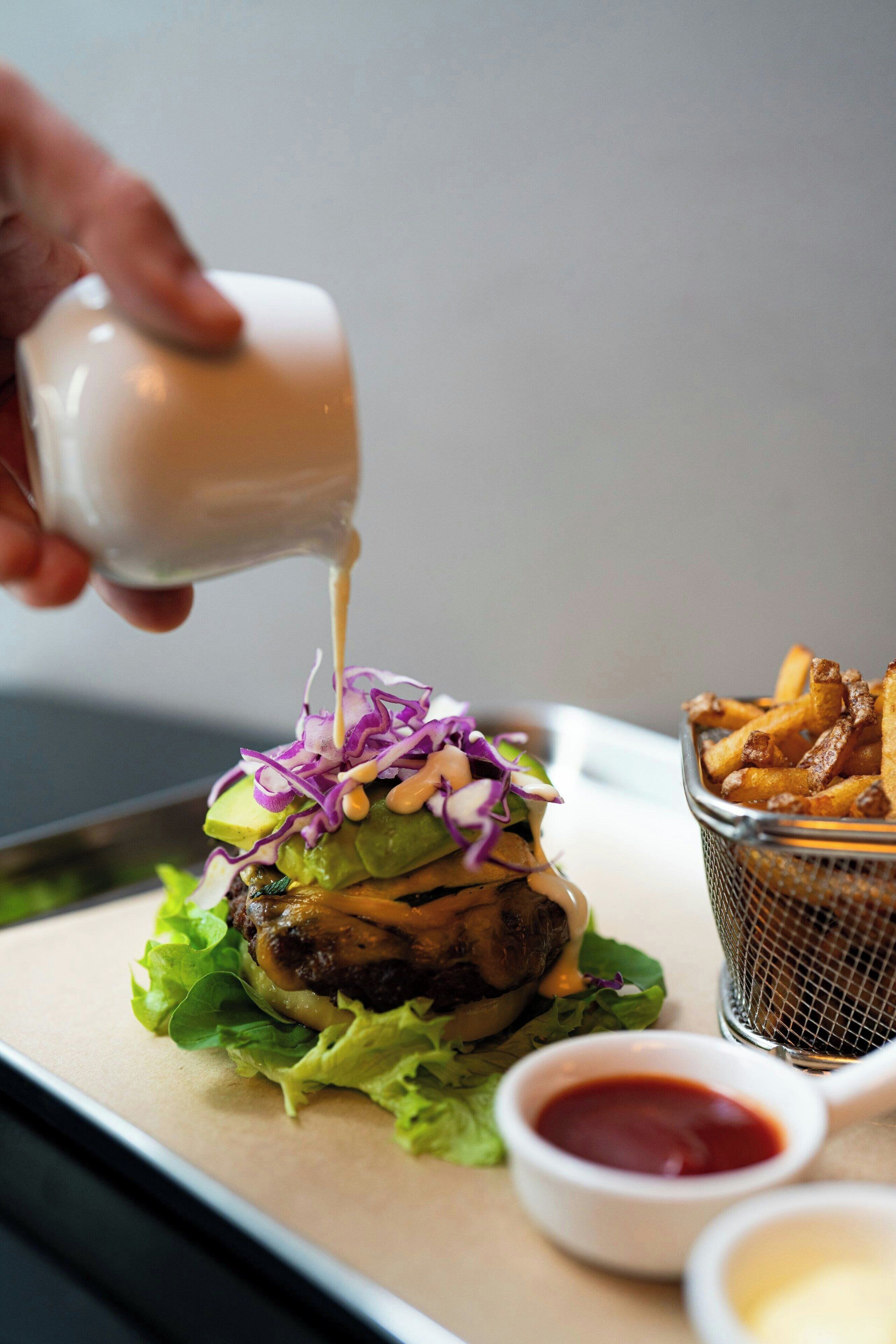 A burger with toppings and a side of fries on a tray.
