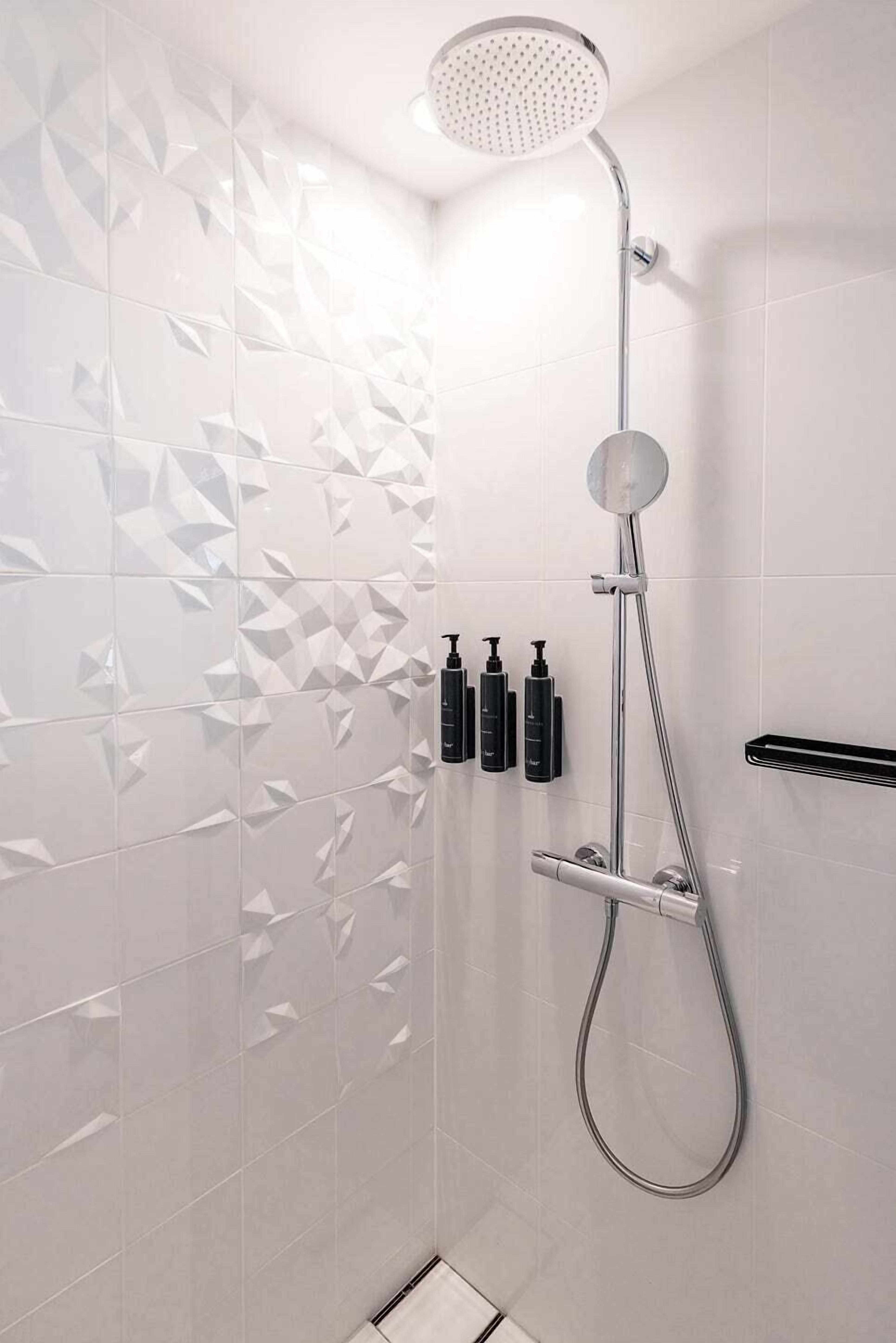 A modern shower with a handheld showerhead and a wall-mounted control.