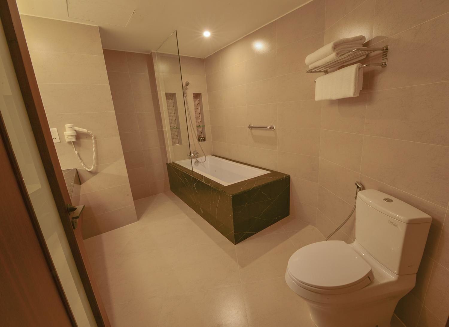 A modern bathroom with a bathtub, toilet, and a glass-enclosed shower area.