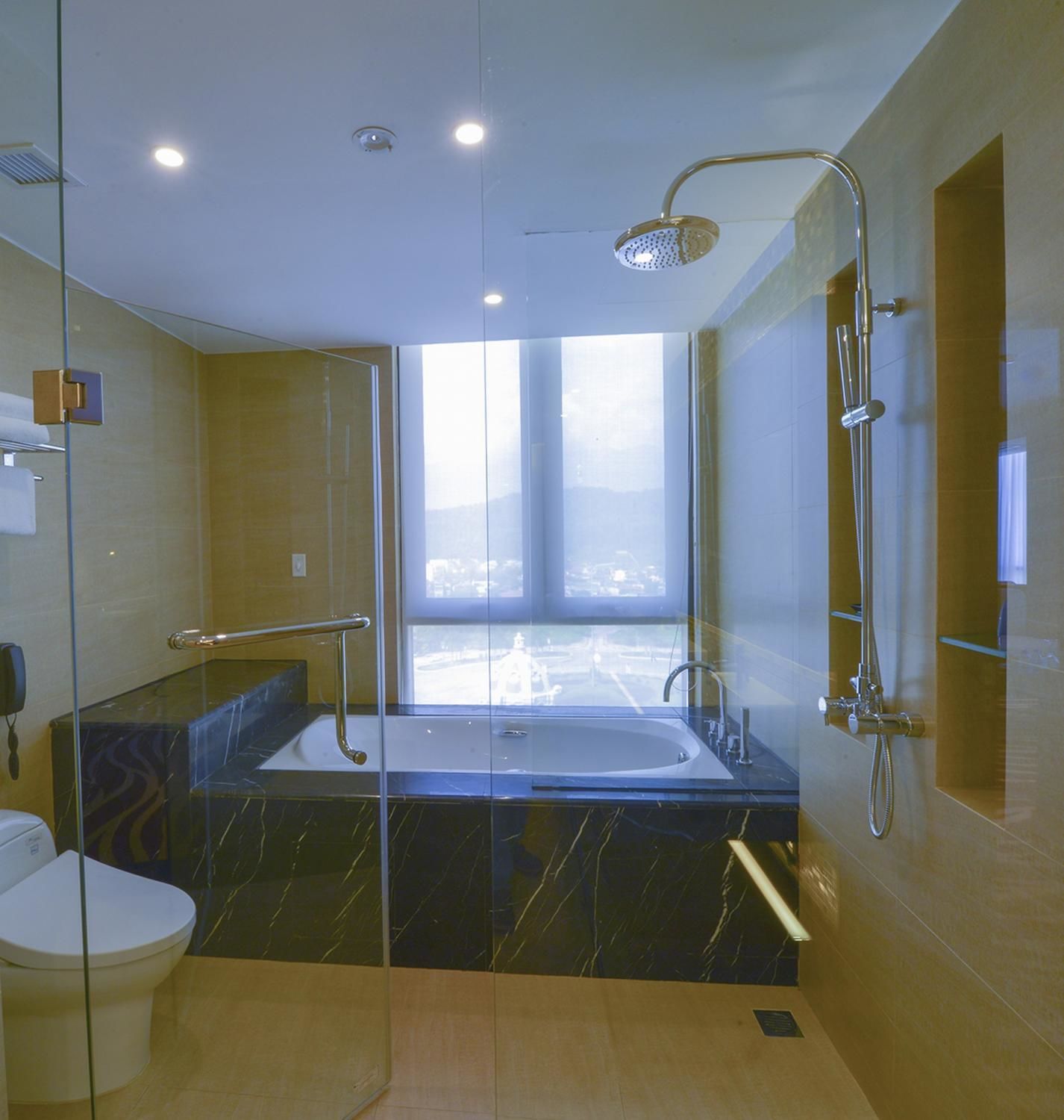 Un baño moderno con ducha envuelta en vidrio, una bañera grande y un inodoro.