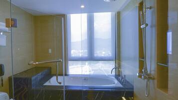 Un baño moderno con ducha envuelta en vidrio, una bañera grande y un inodoro.