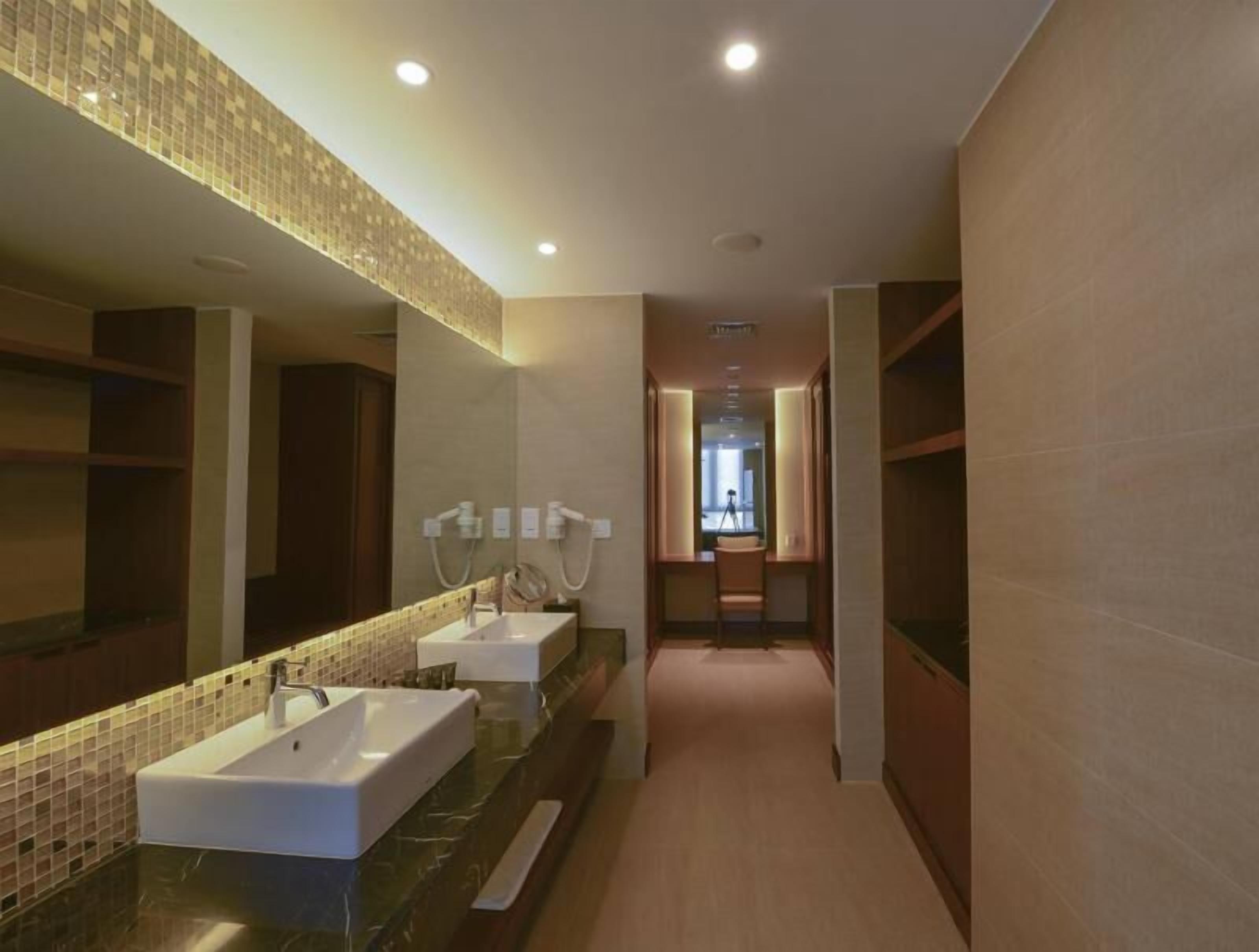 A modern bathroom with two sinks, a large mirror, and a shower area.