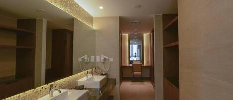 A modern bathroom with two sinks, a large mirror, and a shower area.