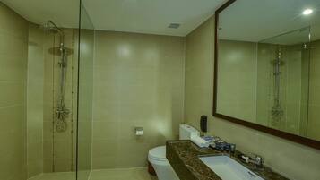 A modern bathroom with a glass-enclosed shower, a white toilet, and a marble sink with toiletries.