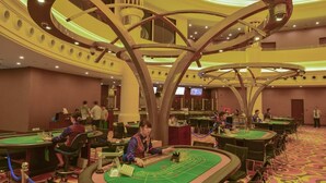 Un casino con múltiples mesas de blackjack, una lámpara de araña grande y un techo alto.