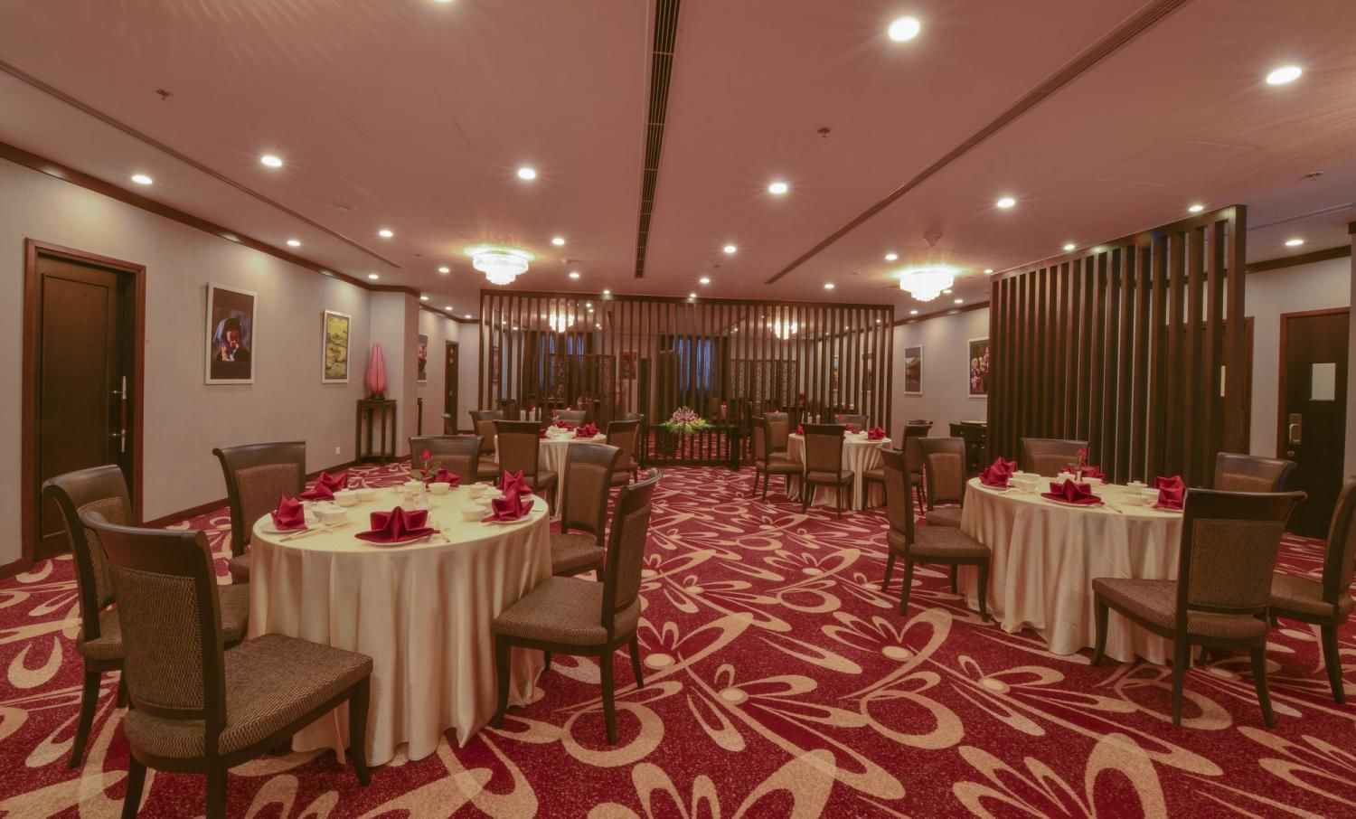 A conference room with round tables, chairs, and a red carpeted floor.