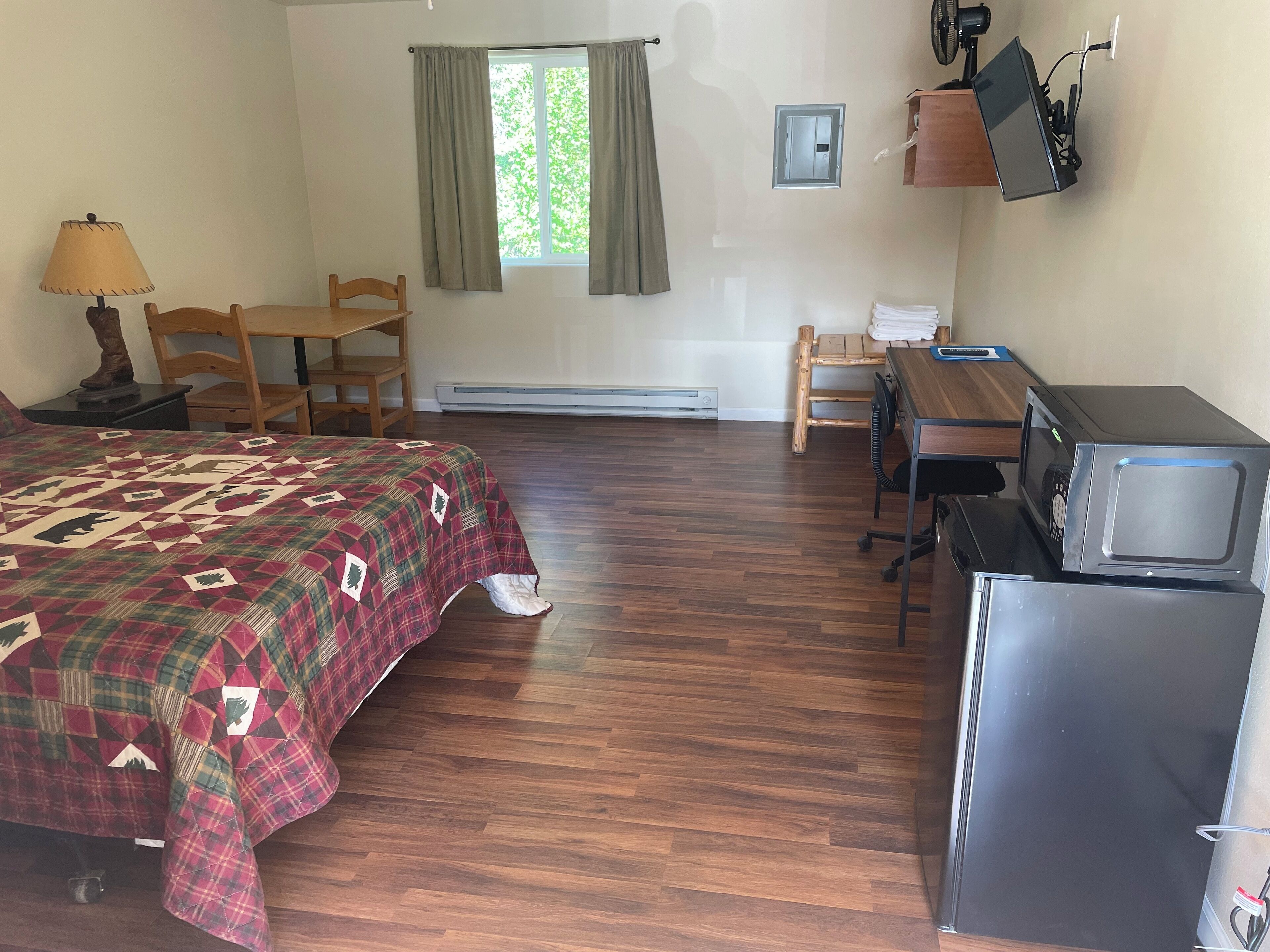 Una habitación con cama, escritorio, silla, microondas y calefacción.
