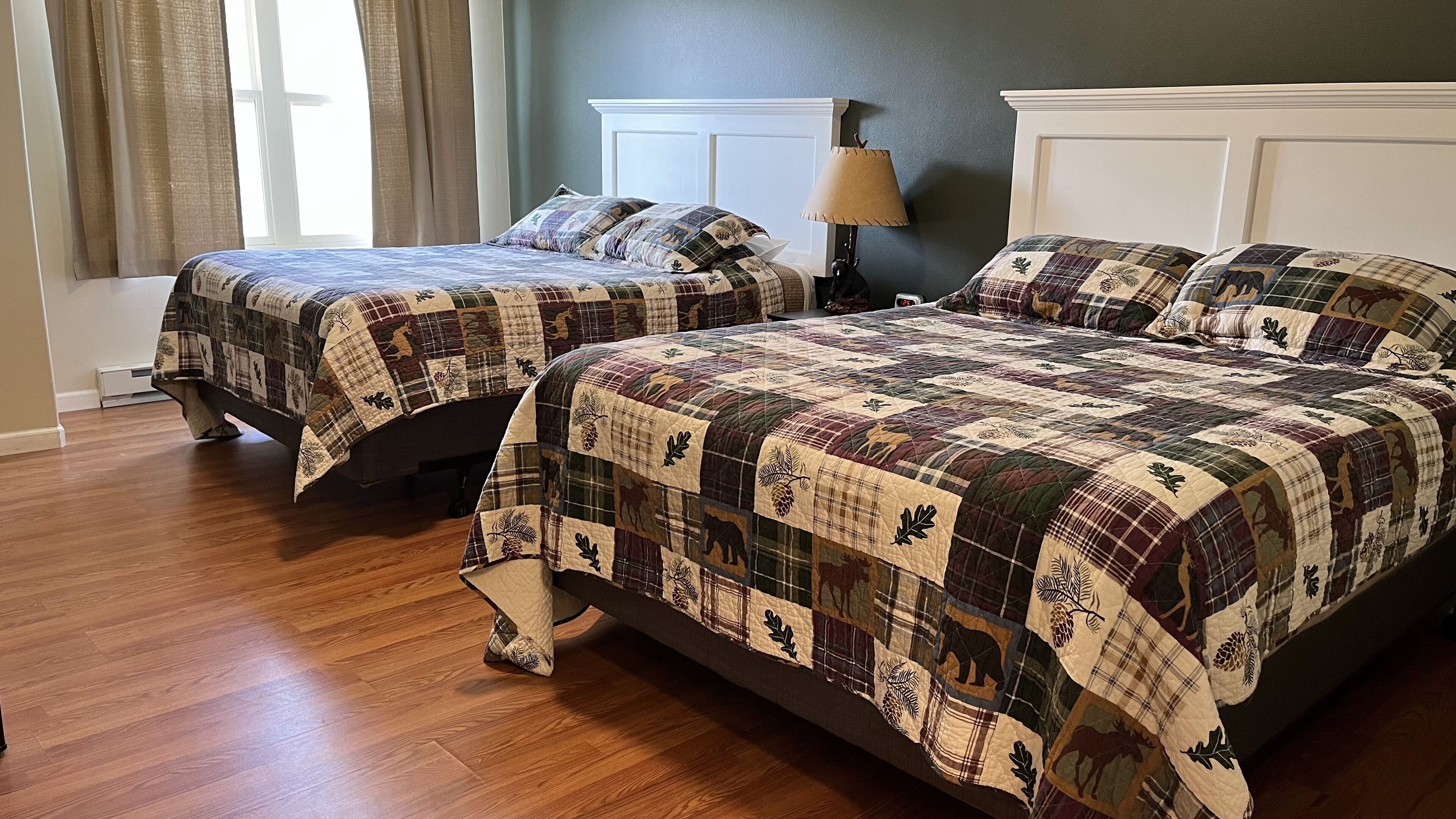 A bedroom with two beds, each covered with a quilt featuring animal prints.