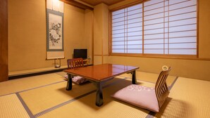 Una habitación japonesa tradicional con suelo de tatami, una mesa baja y un fusuma corredizo.
