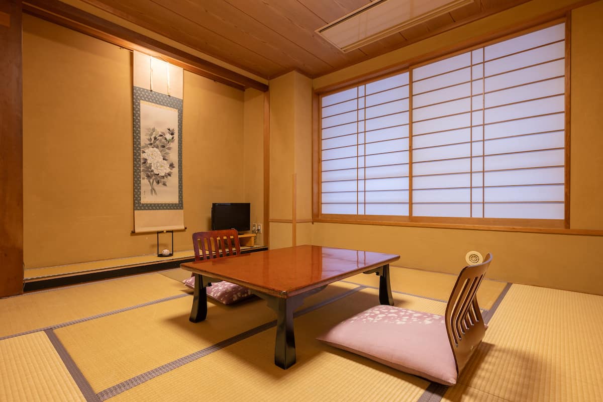 Una habitación japonesa tradicional con suelo de tatami, una mesa baja y un fusuma corredizo.