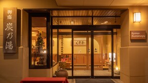 Entrada tradicional de un ryokan japonés con puertas correderas, una mesa roja y un árbol de Navidad.