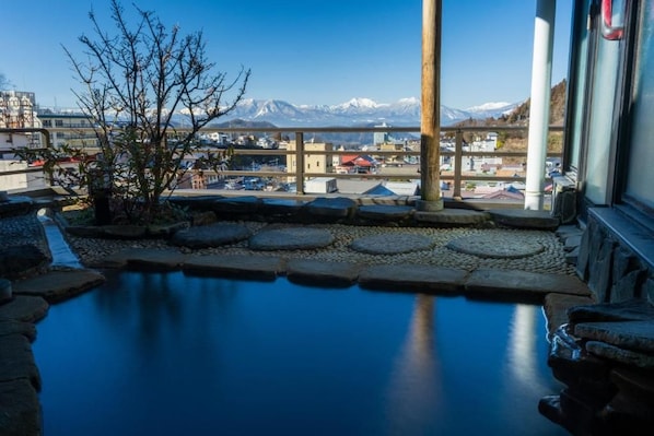 Una piscina con escalones de piedra y vistas a montañas al fondo.