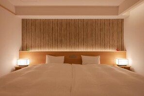 A hotel room with a large bed, wooden headboard, bedside lamps, and a wall-mounted light fixture. - Ryokan Suminoyu (Yamanouchi)