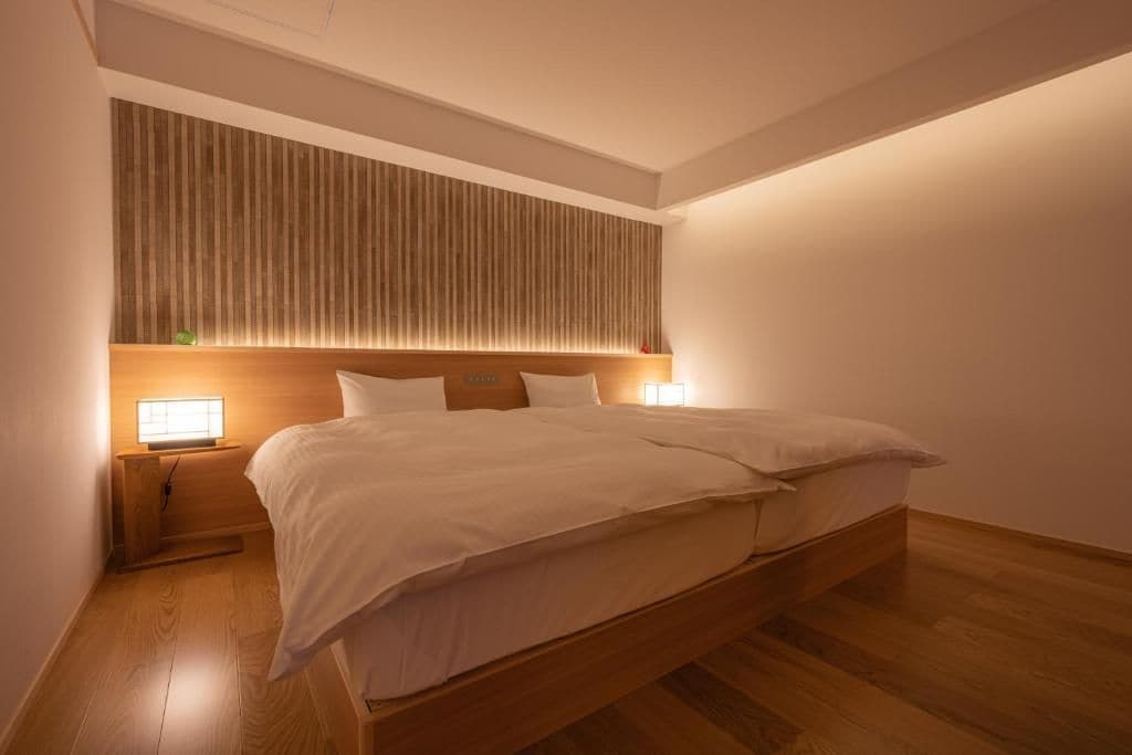 A modern bedroom with a wooden bed frame, a slatted headboard, and bedside lamps.