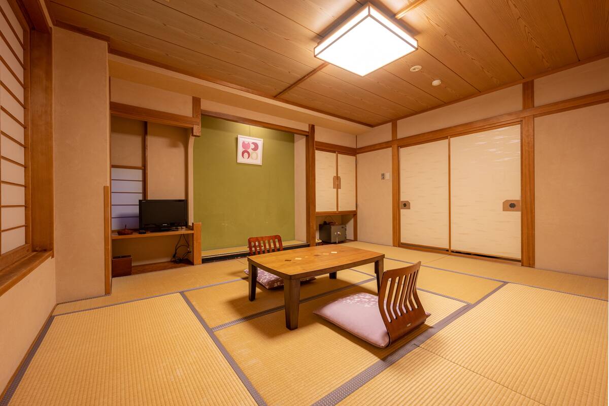 Una habitación japonesa tradicional con suelo de tatami, una mesa baja y puertas correderas.