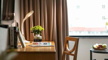 Ein ordentlich aufgeräumter Schreibtisch mit einer Lampe, einer Blumenvase, einem Buch und einer Obstschale.