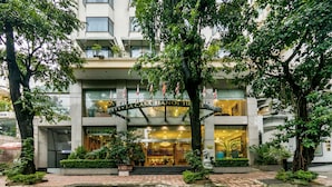 L’entrée d’un hôtel, avec un auvent en verre, des marches menant à la porte et une enseigne indiquant « La Casa Hanoi Hotel ».