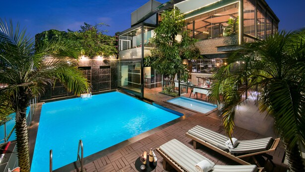 Une maison moderne dotée d’une piscine, de chaises longues et d’un espace bar.