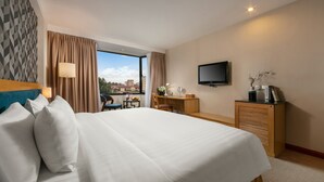 Une chambre d’hôtel avec un grand lit, un bureau, une télévision et une vue sur la ville.