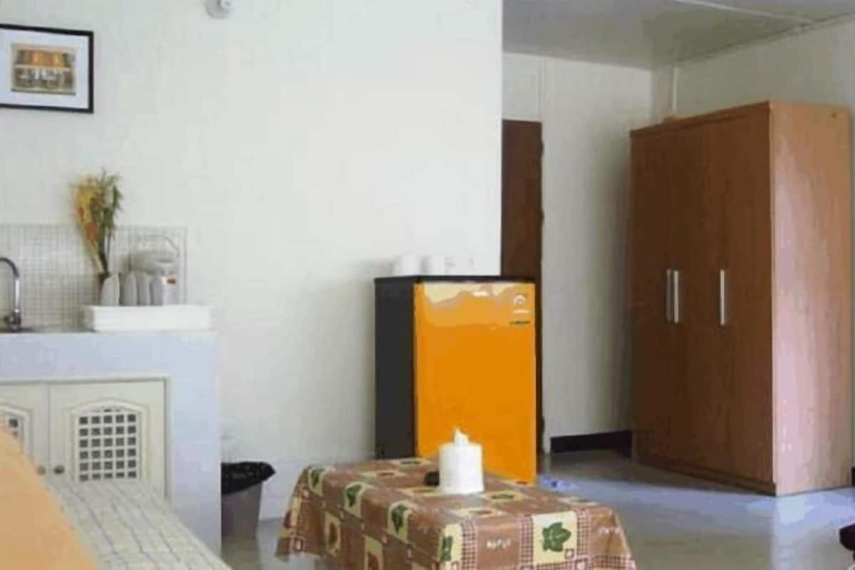 A room with a bed, a table with a tablecloth, a wardrobe, and a sliding glass door.